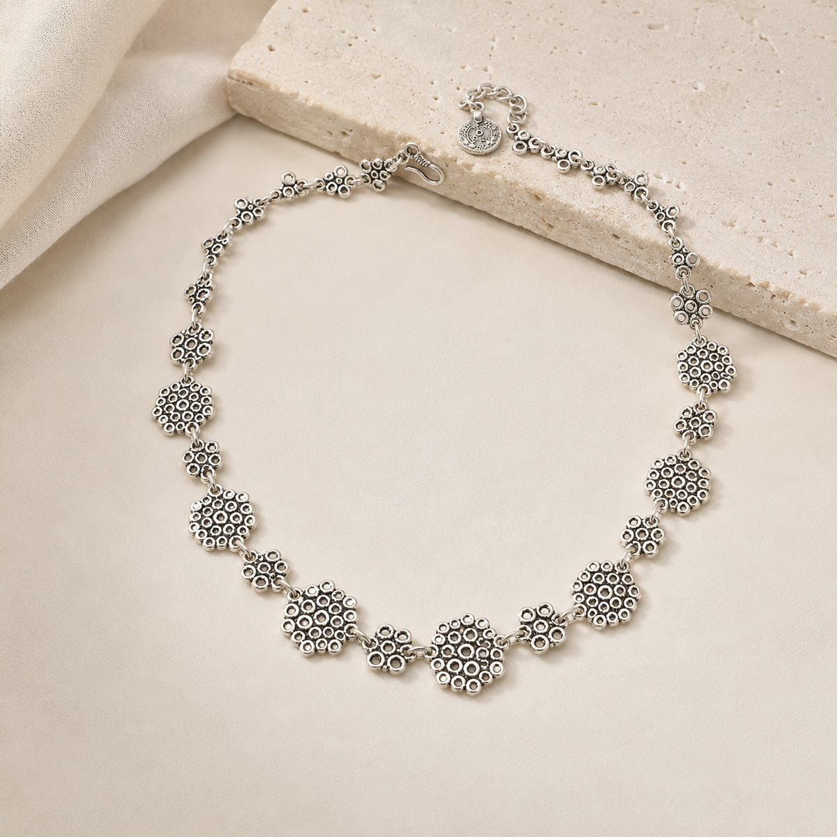 Silver-tone necklace with sculptural linked shapes styled on a white background.
