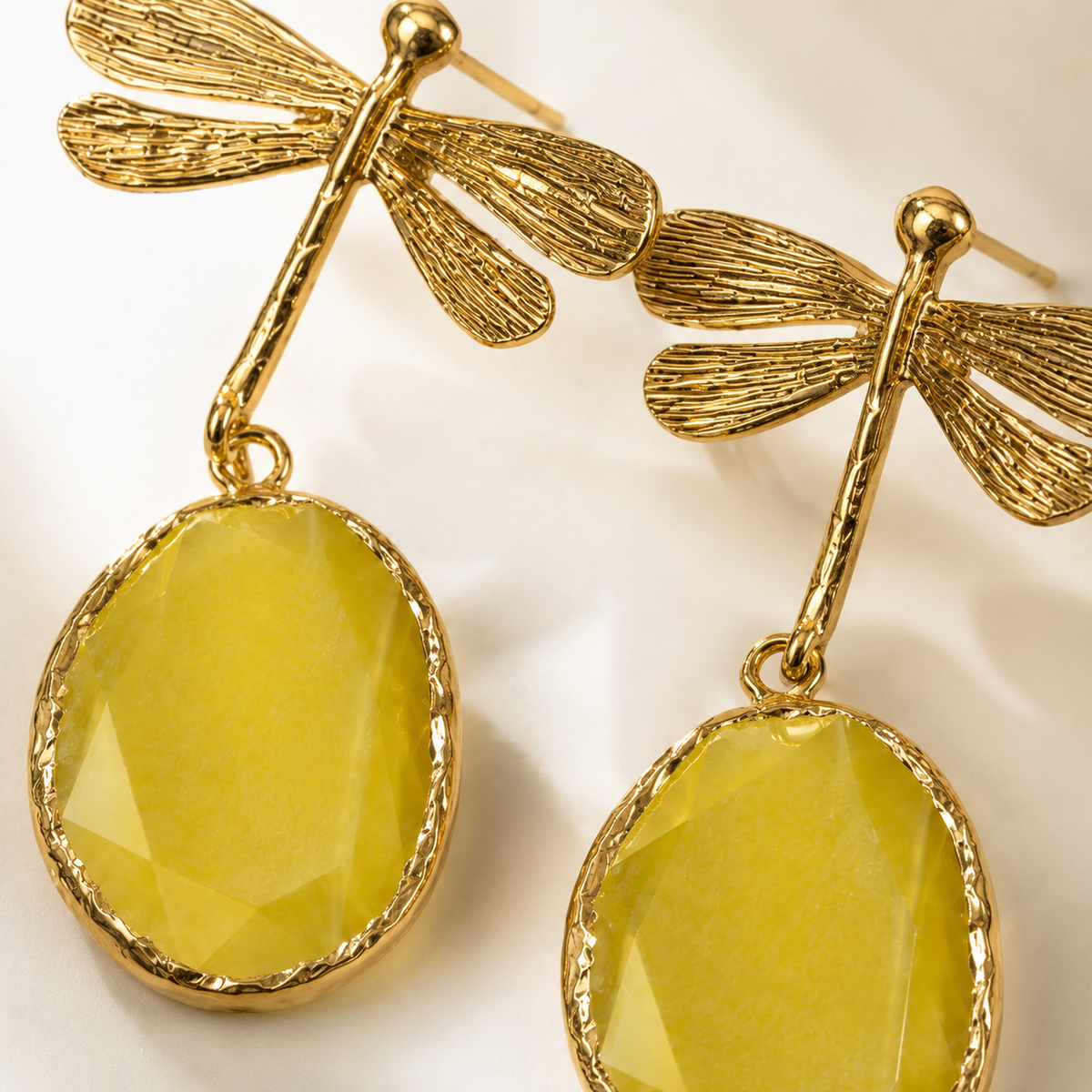 Close view of gold plated dragonfly earrings with textured detailing.