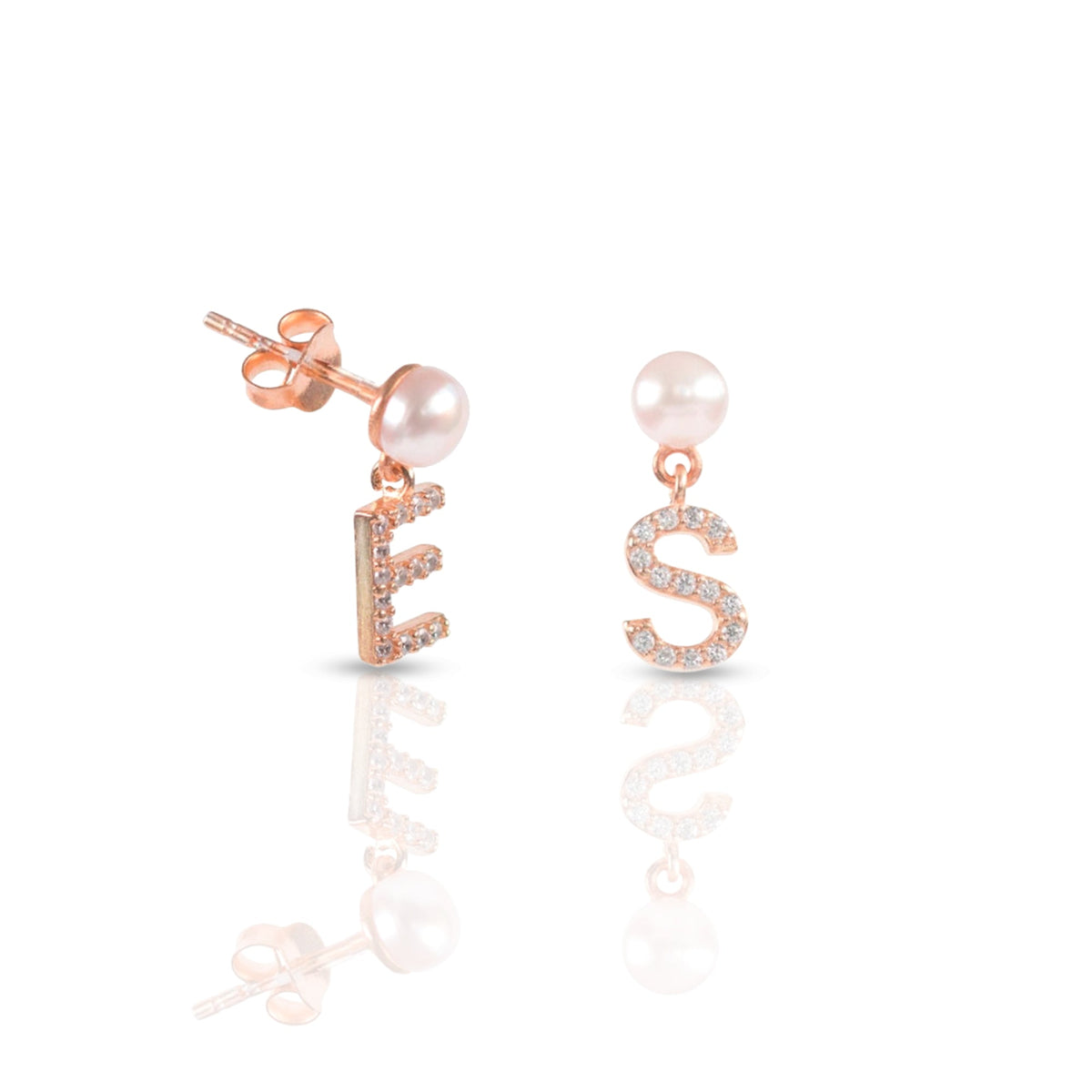 Close view of a pearl stud and sparkling initial charm in gold-tone metal.