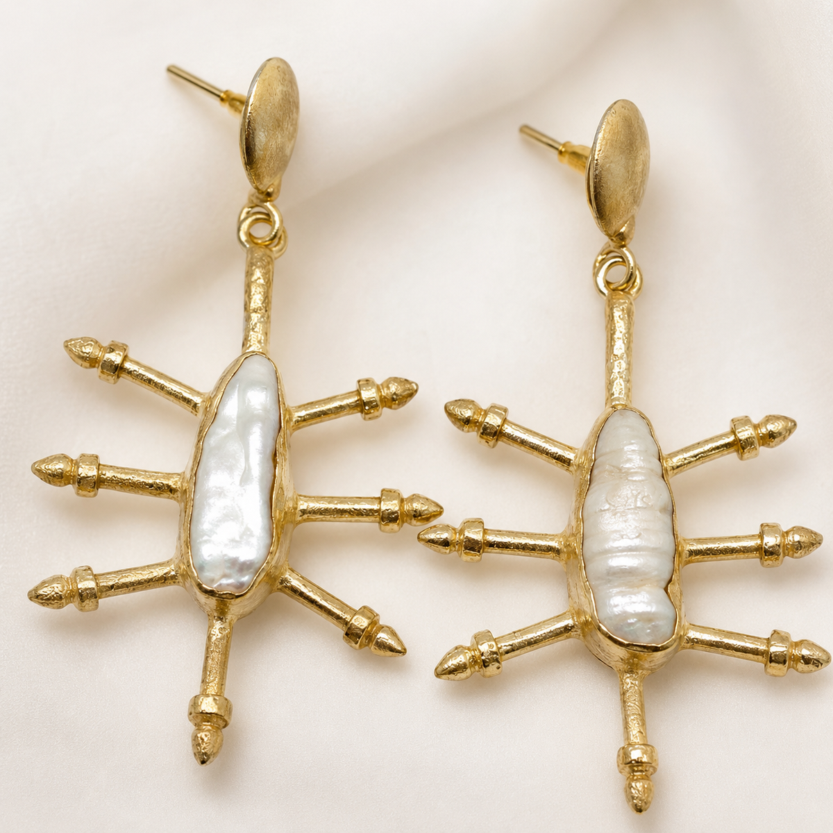 Close view of gold-plated hook earrings with a cushion-shaped blue sapphire look and polished detail.