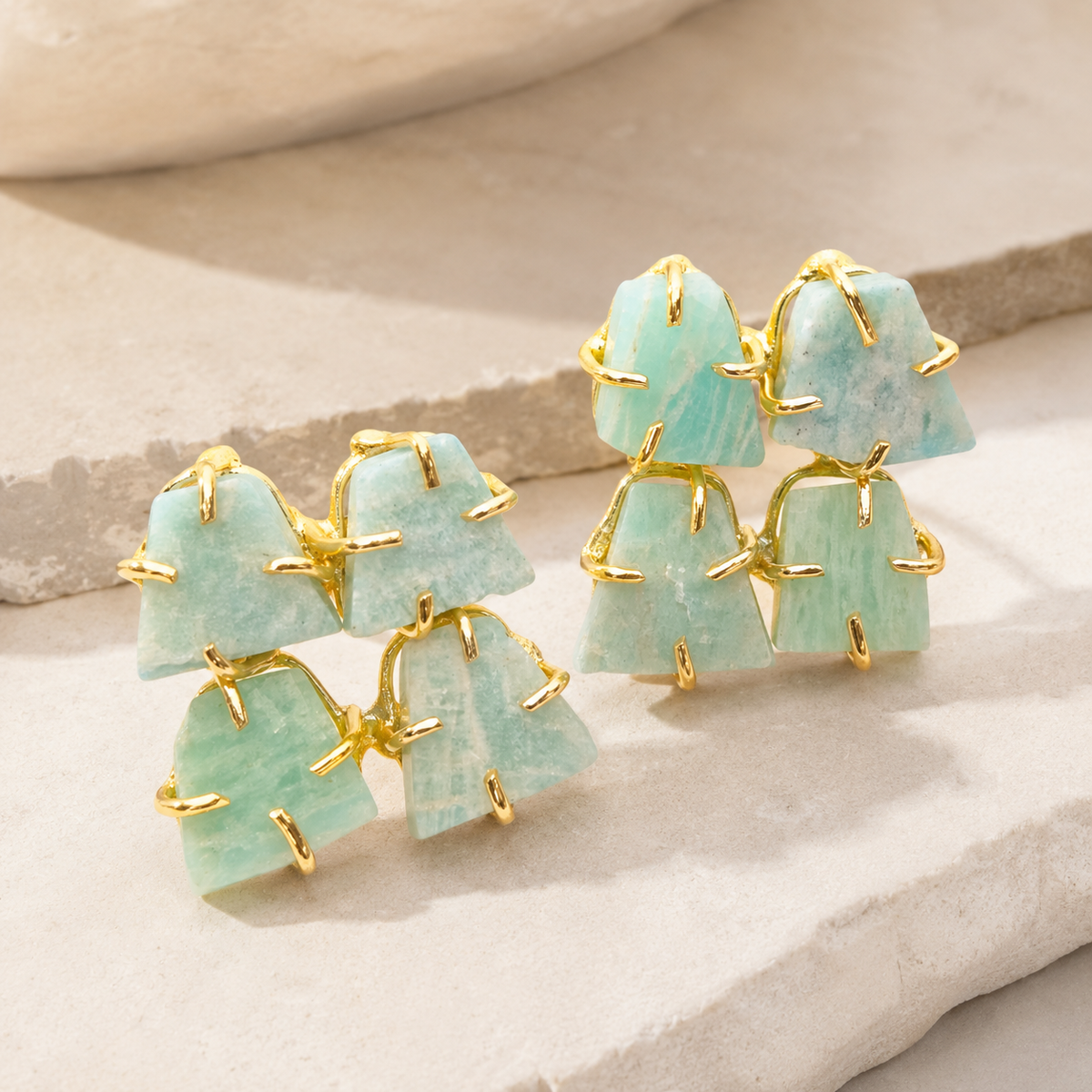 Angled view of rough apatite stud earrings with gold-plated frames and irregular stone shapes.