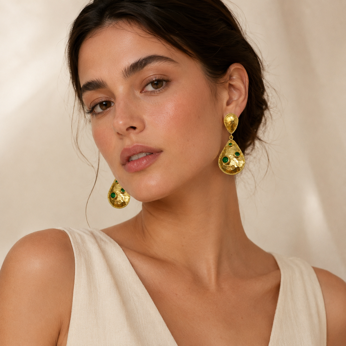 Hammered gold-plated earrings with teardrop shapes and green stone accents.