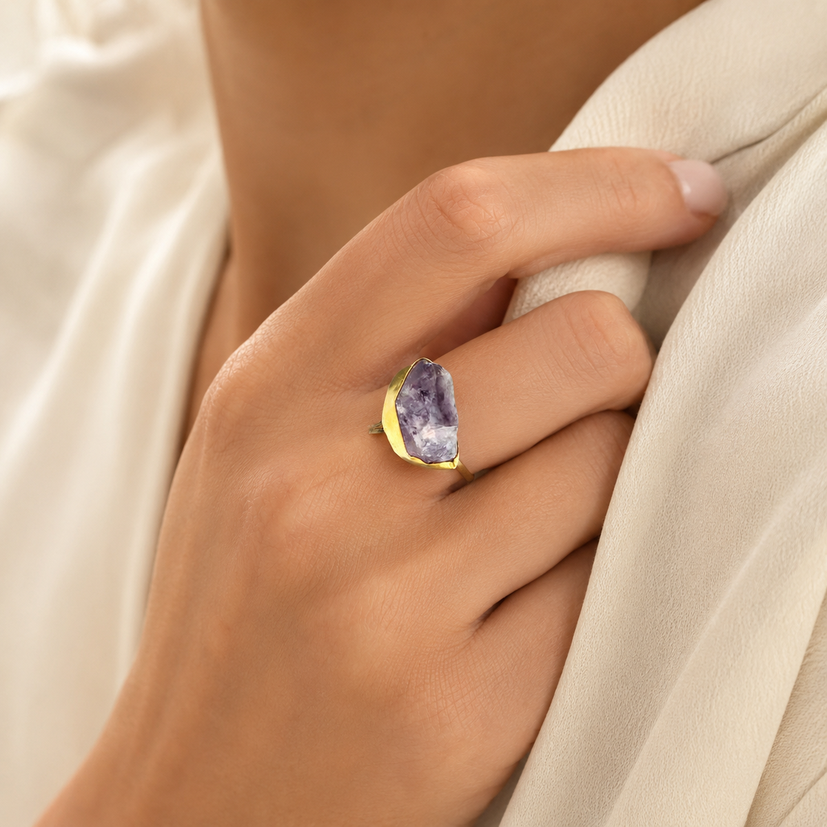 Raw amethyst ring in a gold-plated setting shown from the side.