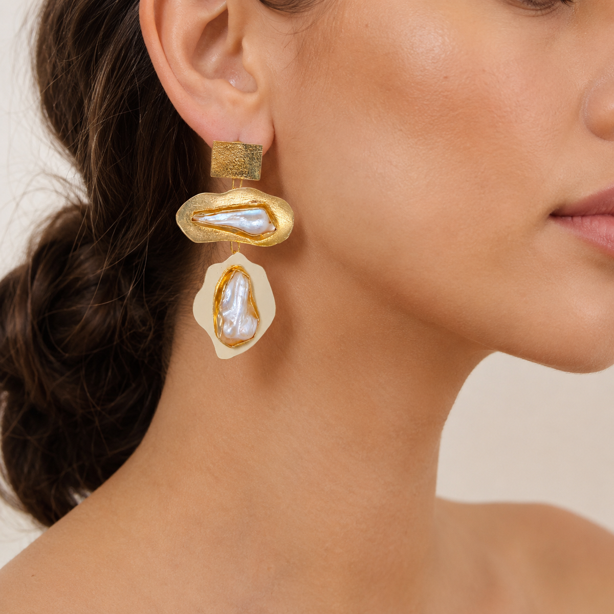 Baroque pearl statement earrings shown from the front with gold-plated sculptural shapes.