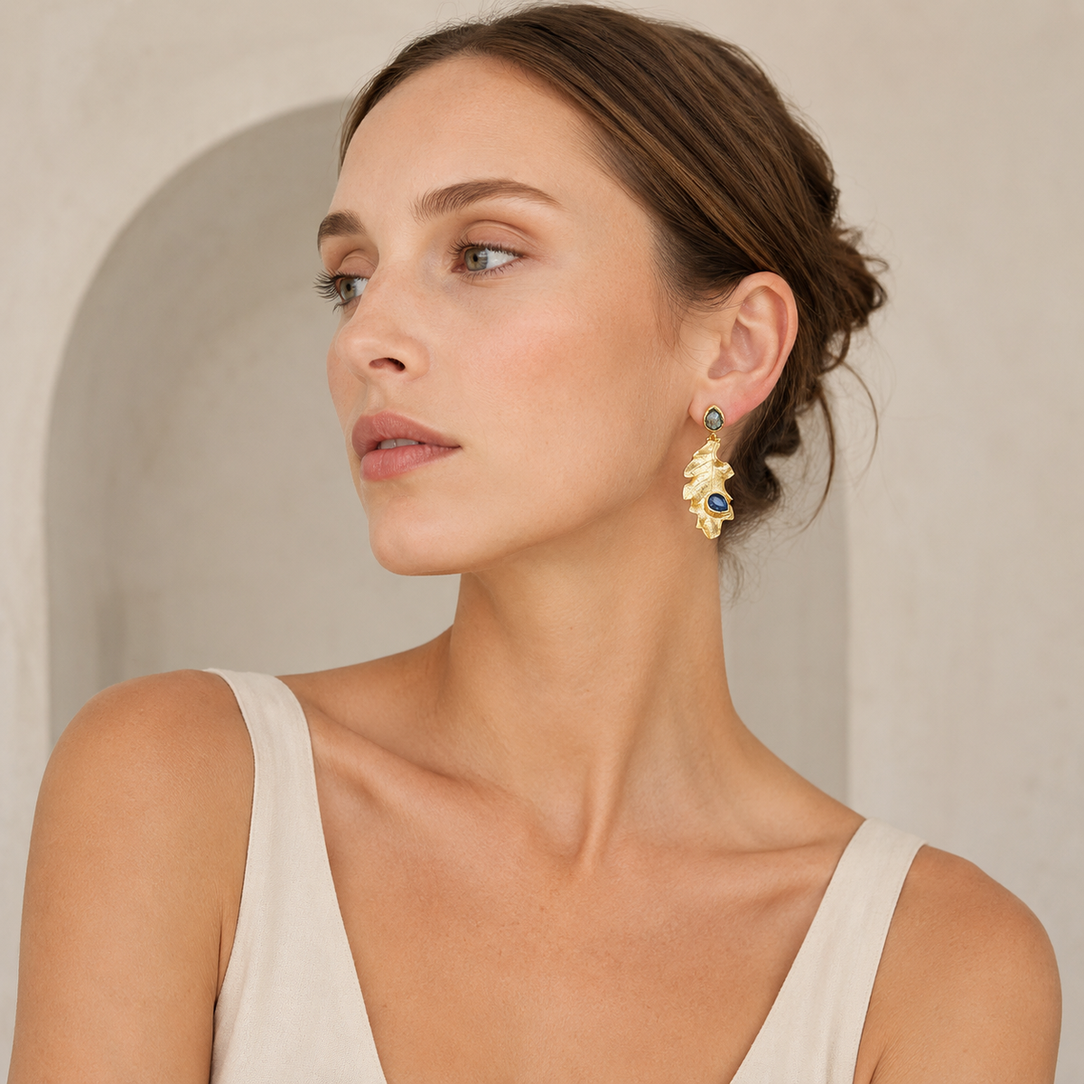 Gold leaf earrings with deep blue stone accents in a clean product view.