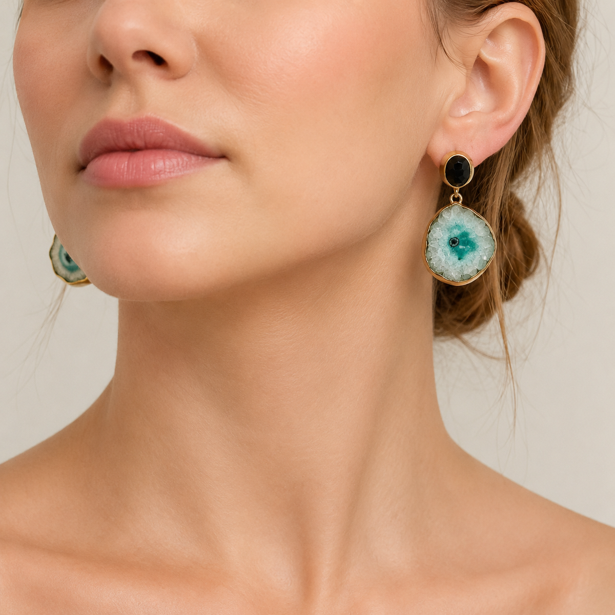 Pair of gold-plated drop earrings with black stone studs and pale green stone drops.