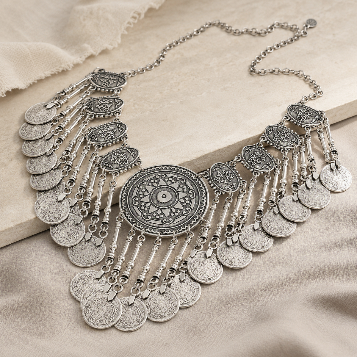 Angled view of a silver-tone fringe medallion necklace with detailed texture.