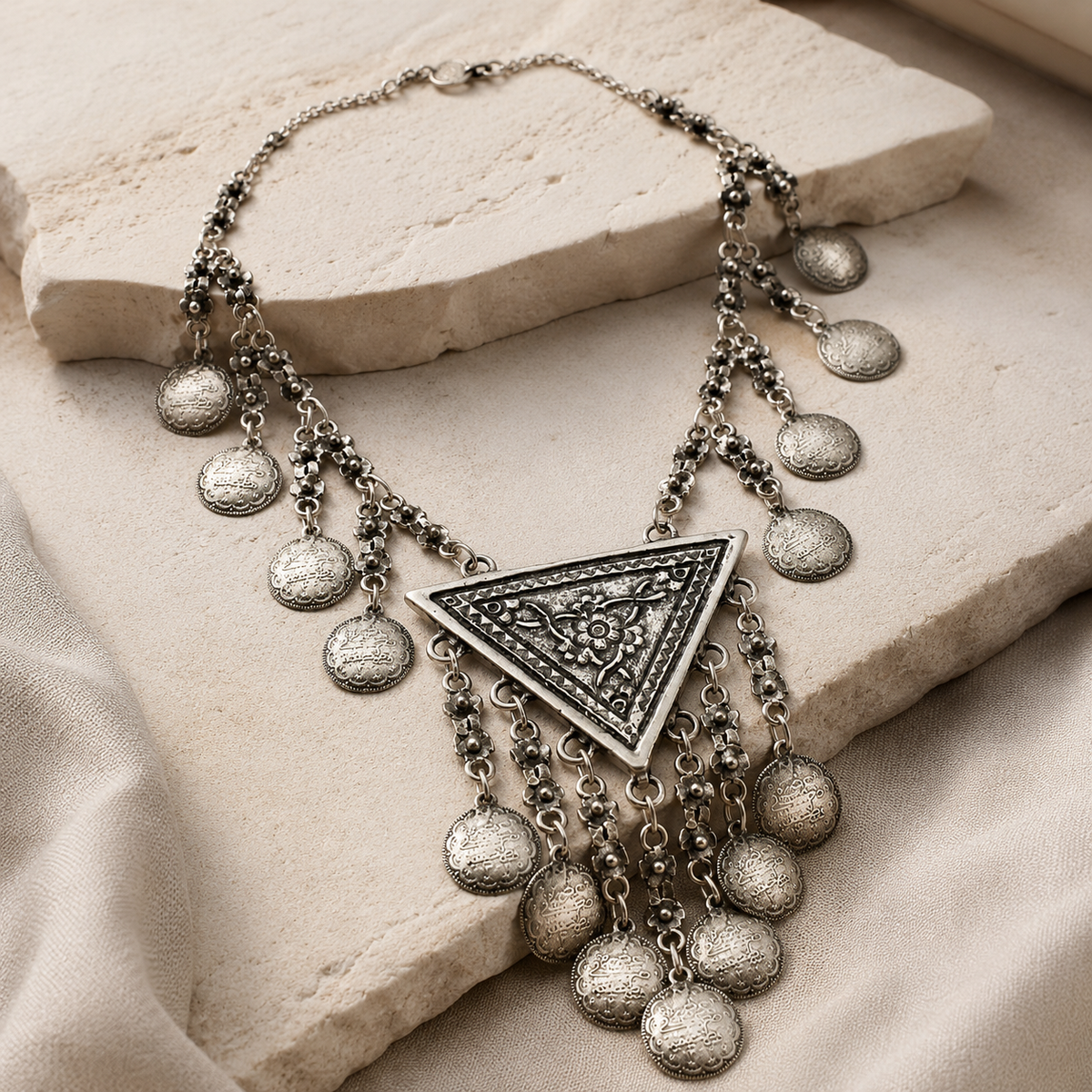 Angled view of a silver-tone crescent necklace with layered coin charms.
