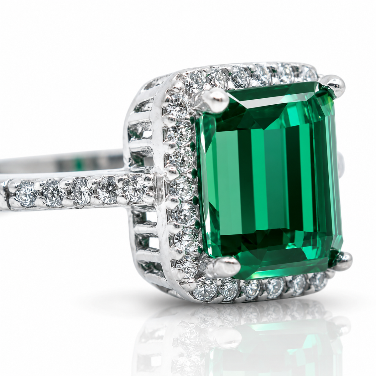 Close view of the emerald cut green stone and halo setting.