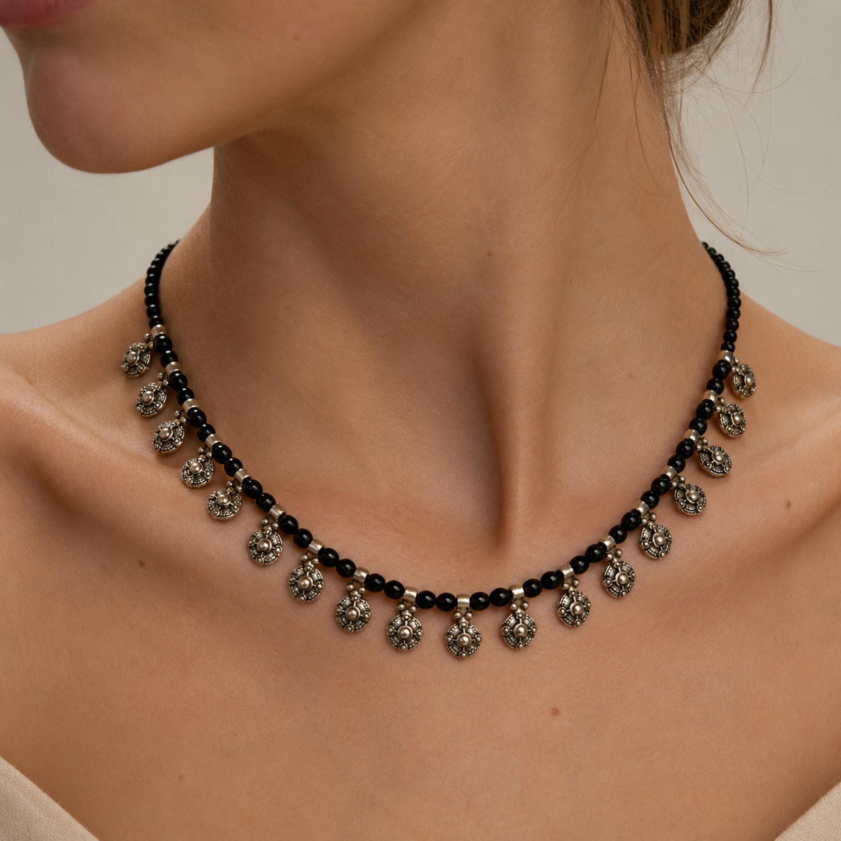 Black bead necklace with oval charm drops and silver-tone accents.
