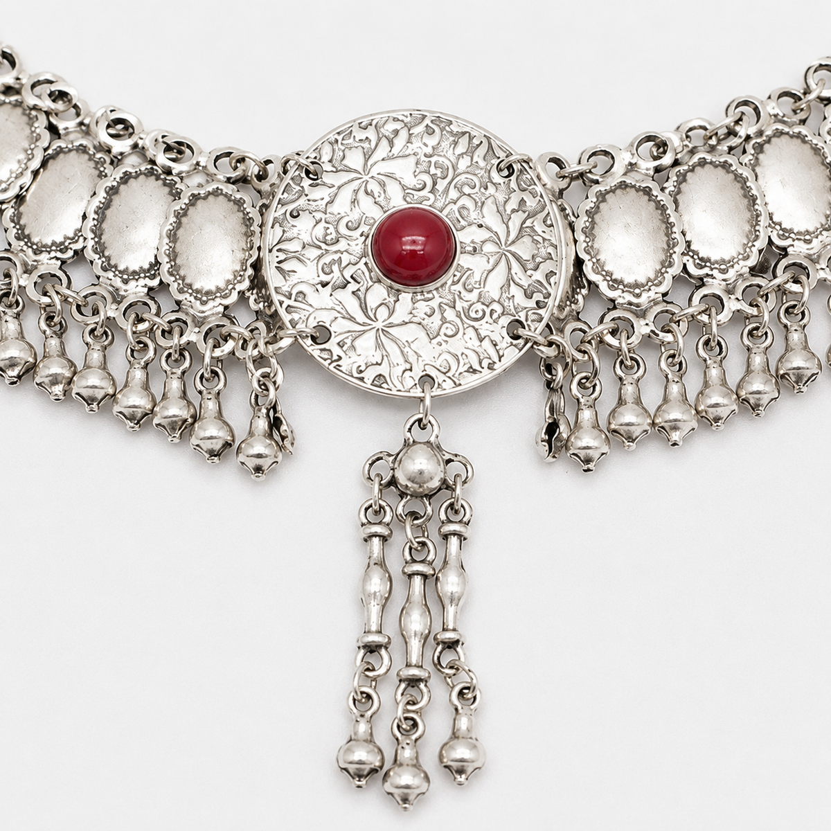 Close view of the silver-tone necklace with textured disc accents and dangling drops.