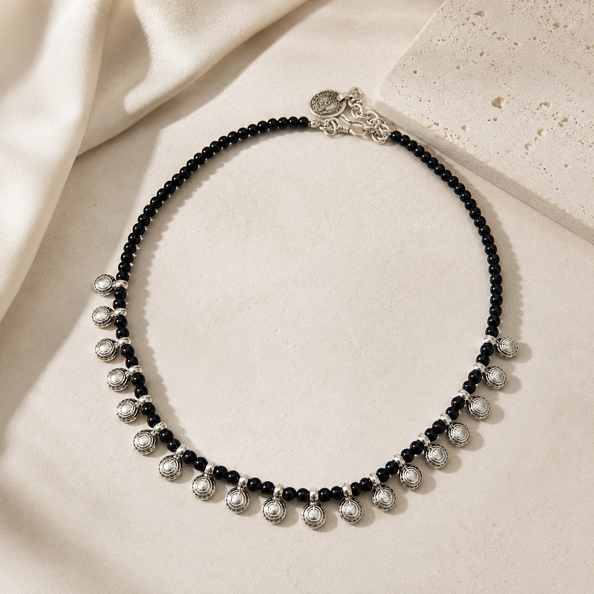 Black bead charm necklace styled on a white background.