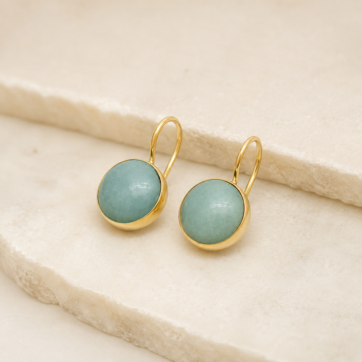 Angle view of clear quartz drop earrings with gold-plated hooks.