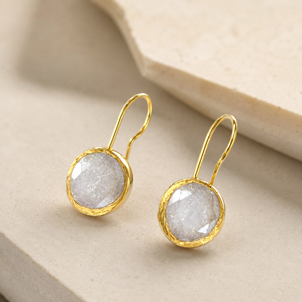 Angle view of round clear CZ gold-plated drop earrings.