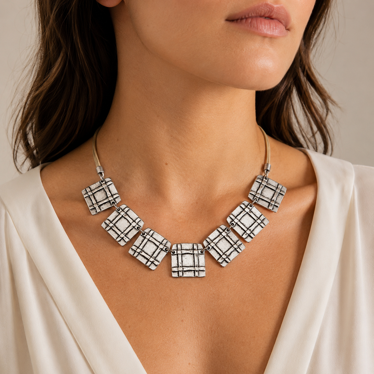Beige cord necklace with square grid pendants shown on a white background.