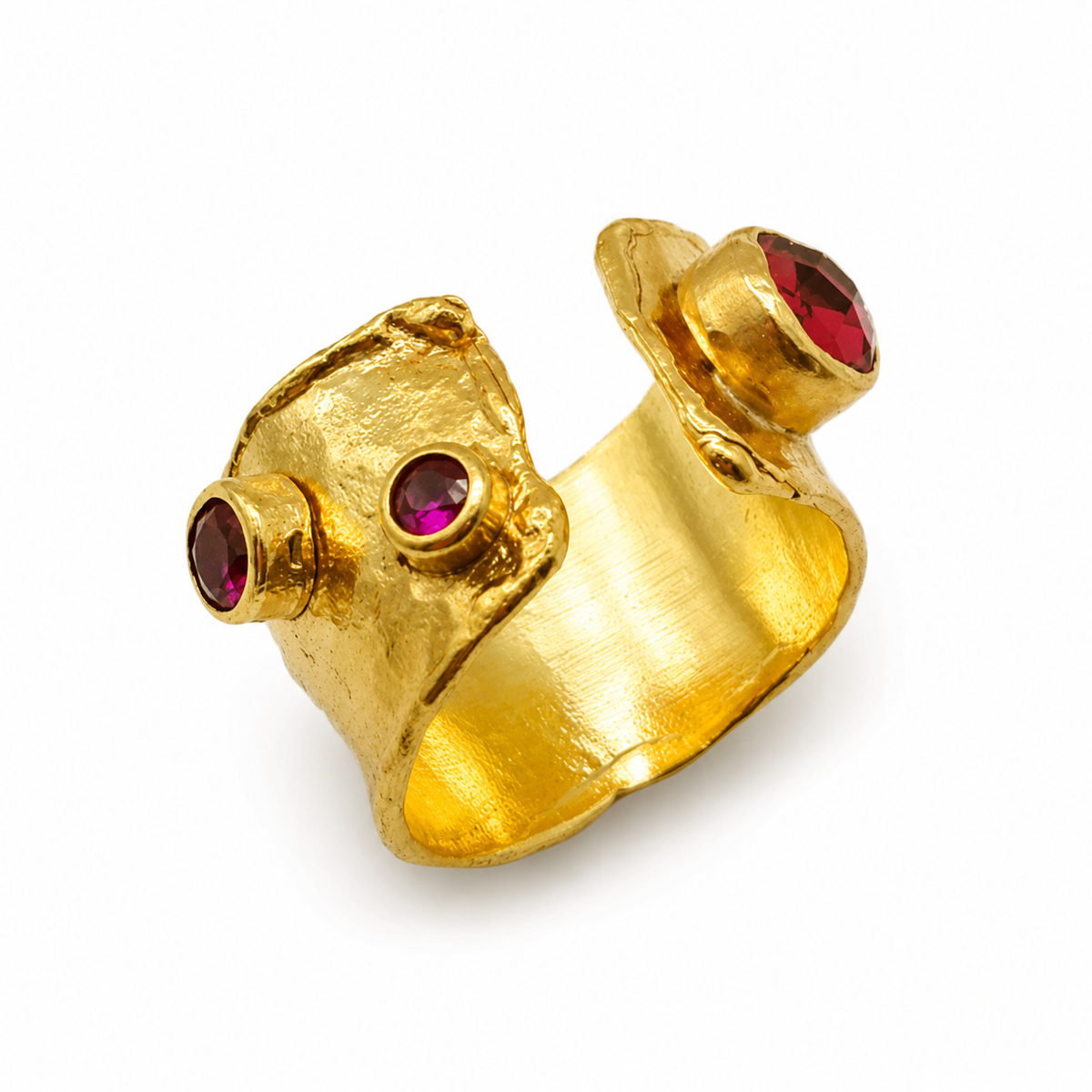 Gold-plated open cuff ring with garnet red stones and a textured sculptural shape.