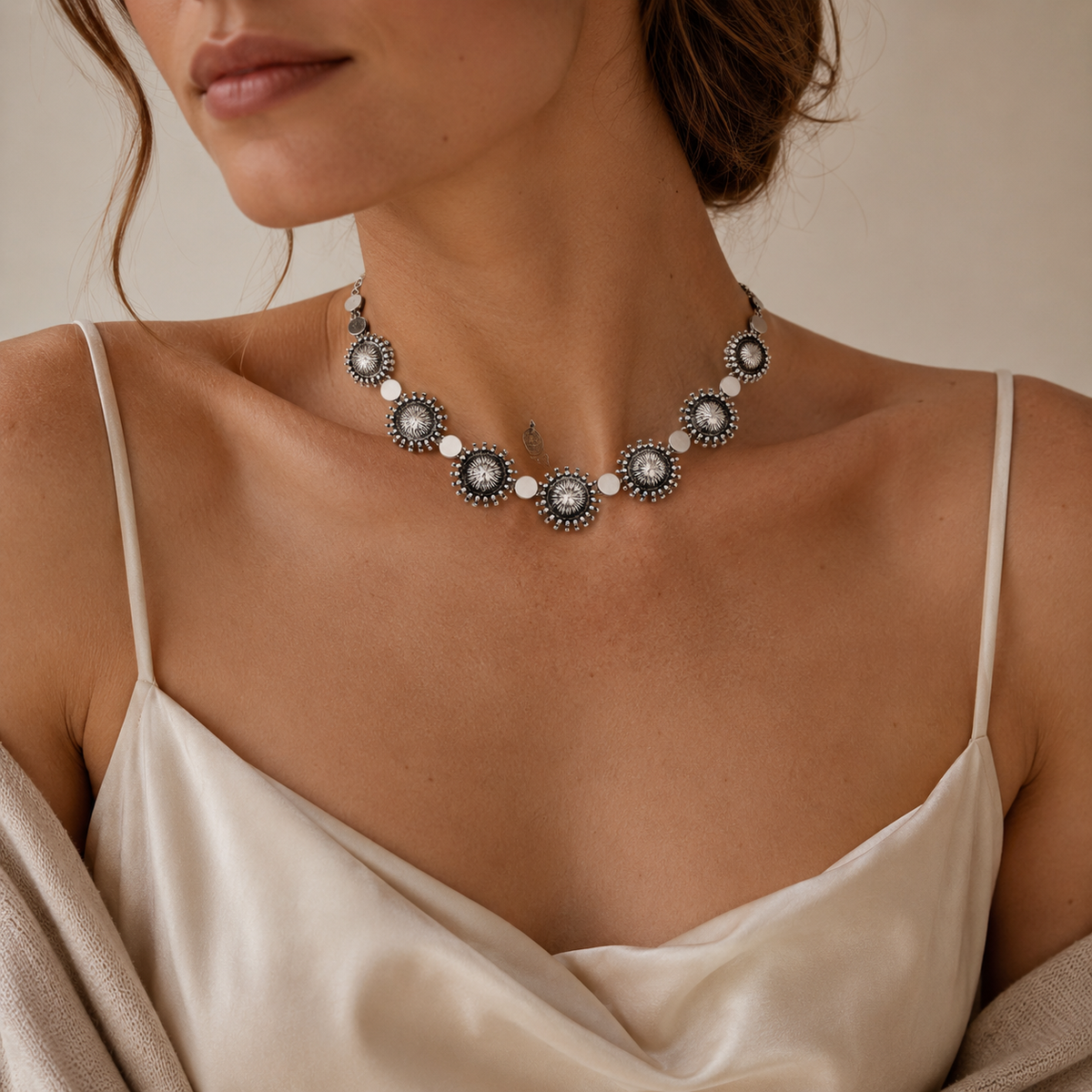 Silver-tone collar necklace with repeating sunburst disc elements.