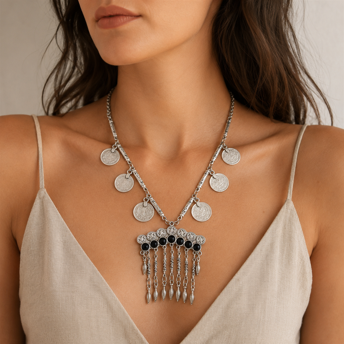 Front view of a silver-tone necklace with black stone accents and dangling fringe details.