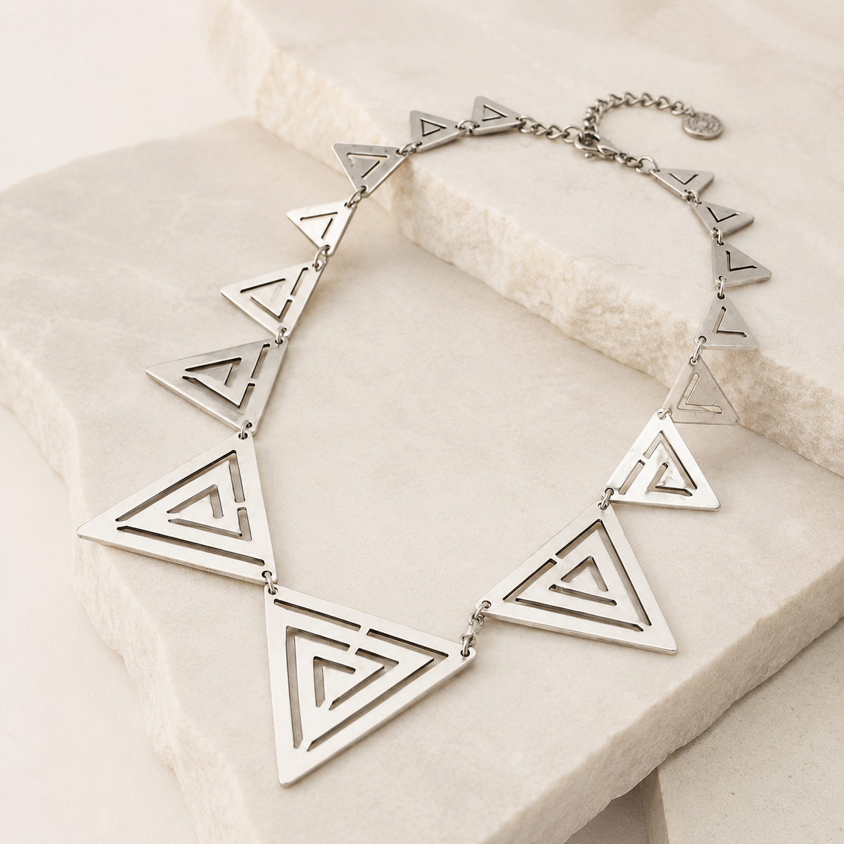 Angled view of the triangle cutout necklace showing the sculptural pendant shapes.