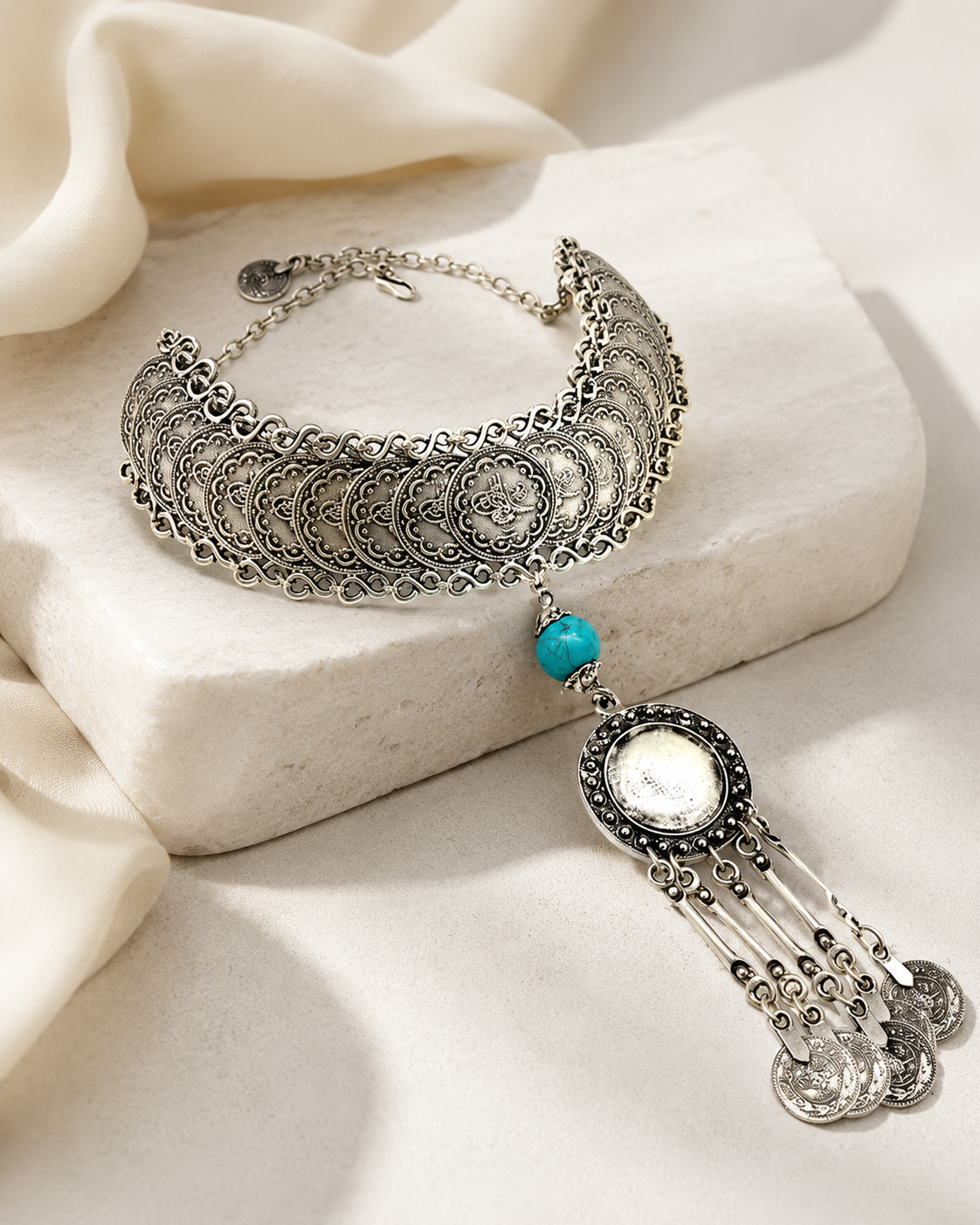 Silver-tone statement necklace with layered coins and a tassel drop.