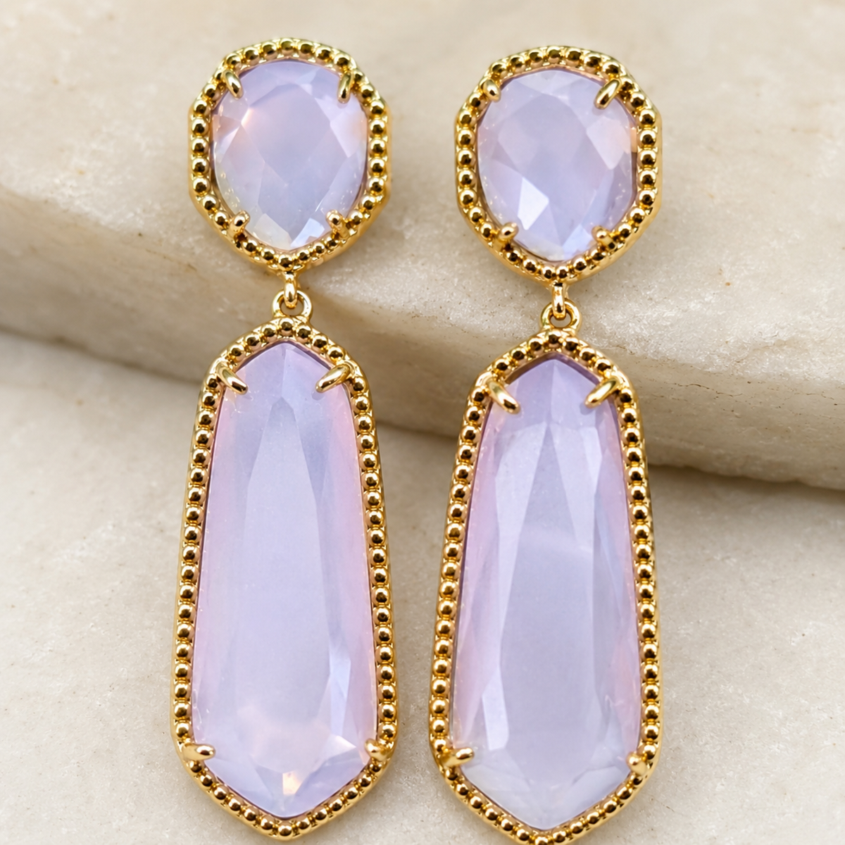 Close view of lavender cat eye-inspired stones in a gold-tone pave setting.