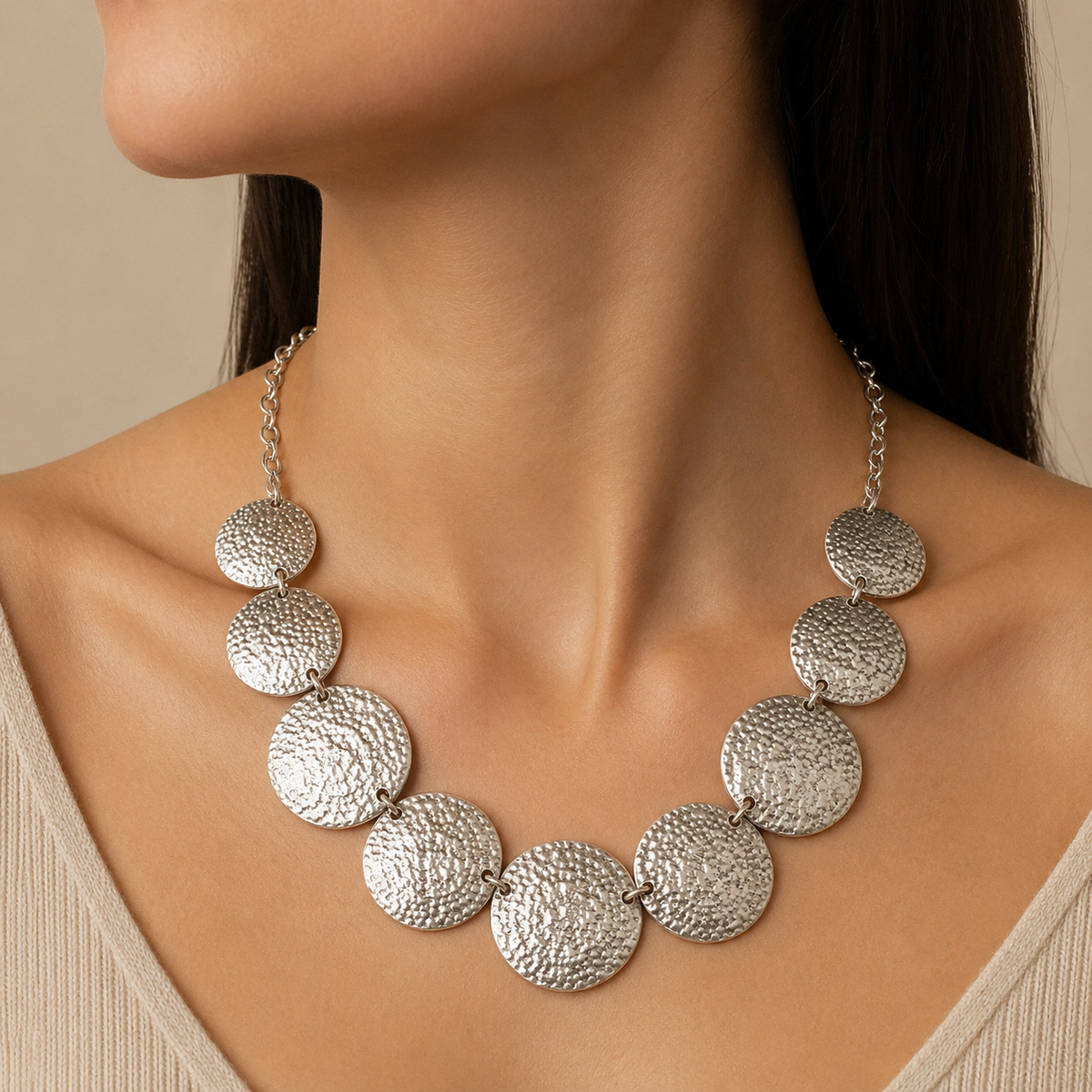 A hammered disc statement necklace arranged on a white background.