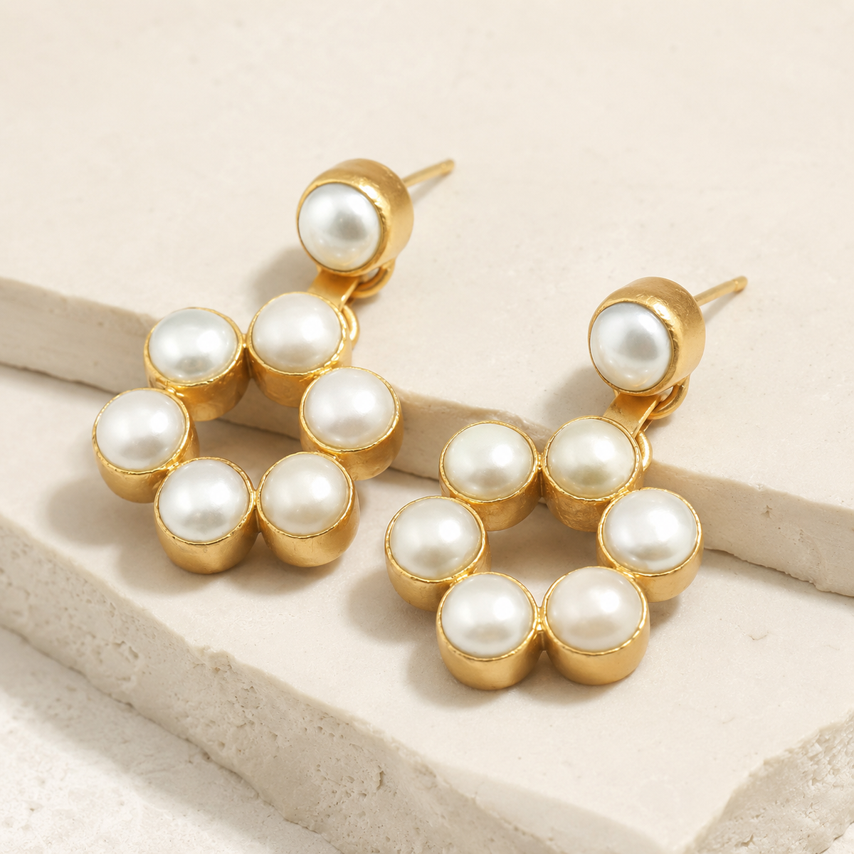 Angled view of gold-plated hoop drop earrings with round pearl accents.