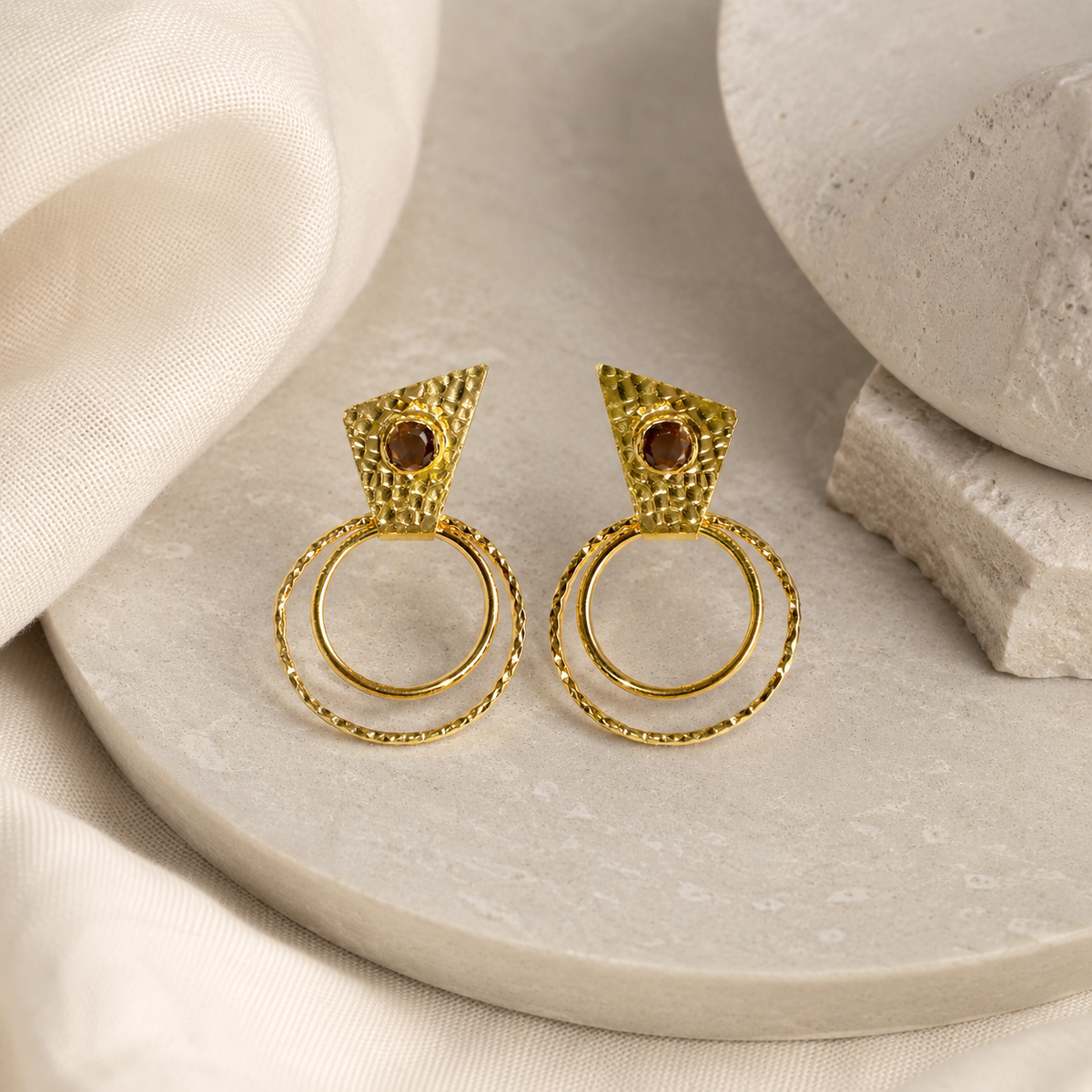 Pair of gold-plated drop earrings with bold circle shapes and textured detail.