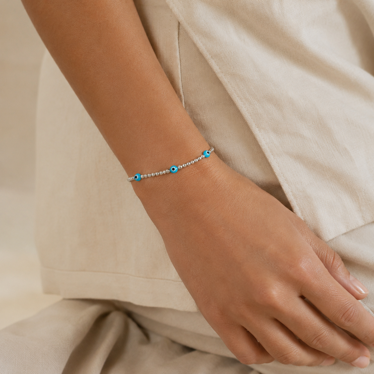Silver beaded bracelet with three blue evil eye charms.