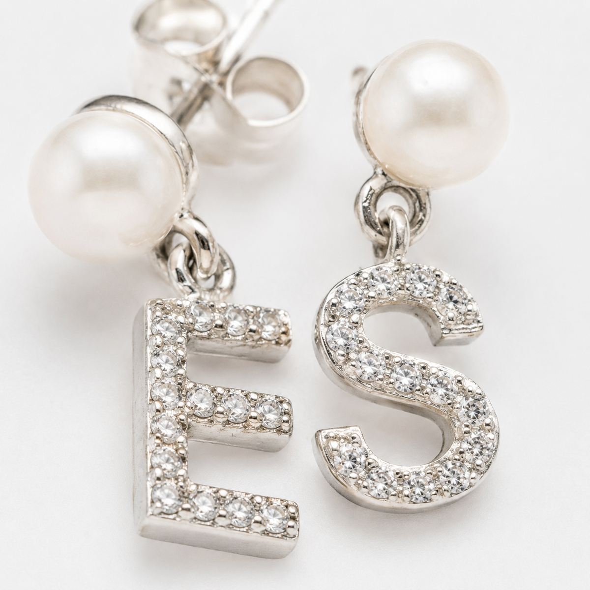 Gold-tone initial dangle earrings with pearl studs and crystal-like accents.