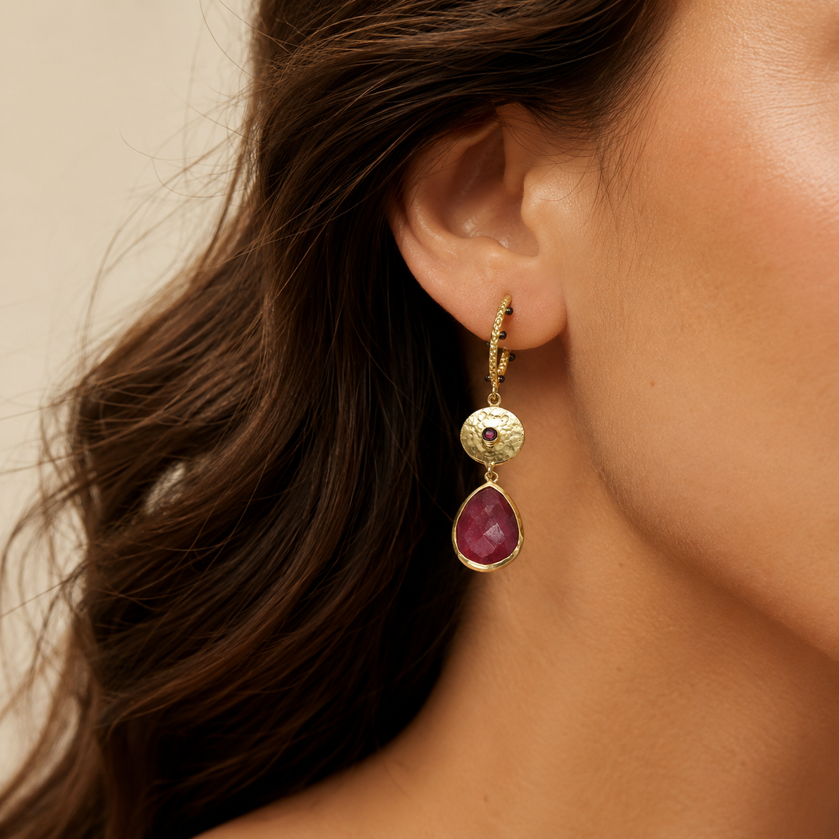 Long gold-plated statement earrings with textured links and red faceted drops shown on a model.