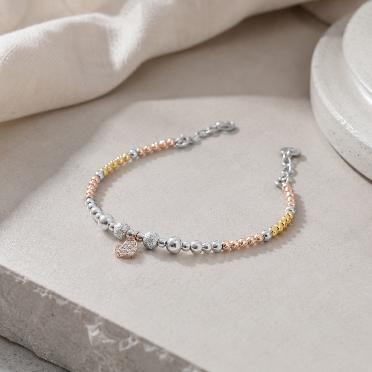 A heart bracelet with gold and silver beads styled on a clean white background.