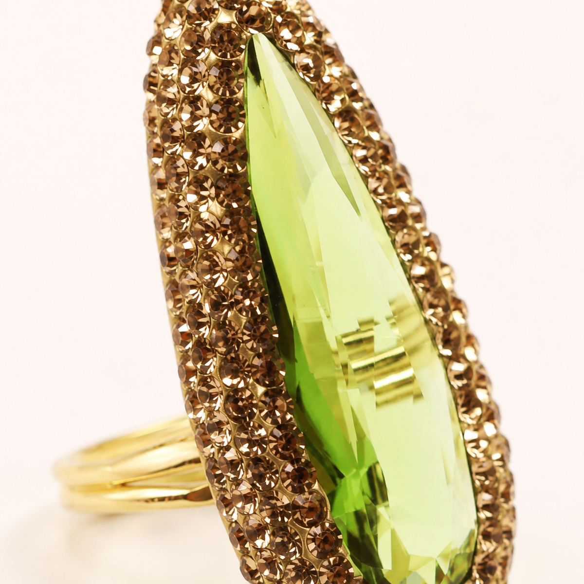 Close view of the textured gold-tone setting around the green center stone.
