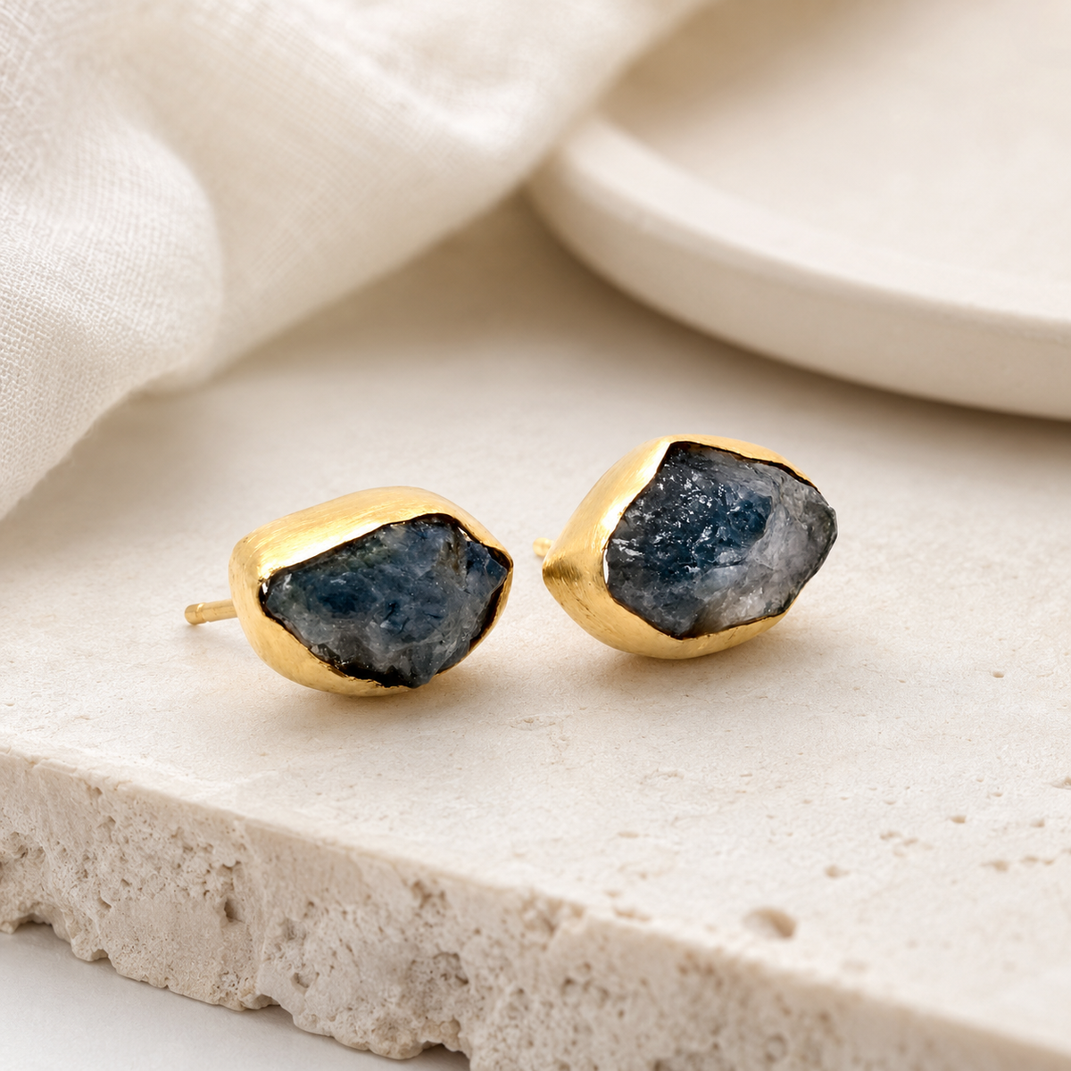 Pair of gold-plated heart stud earrings with red crystal detail on a white background.