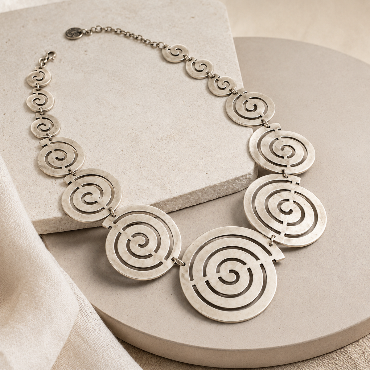 Angled view of the spiral circle statement necklace with linked round pendants.