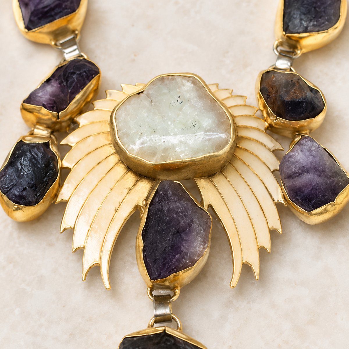 Close view of the necklace showing purple stone details and polished gold-tone settings.