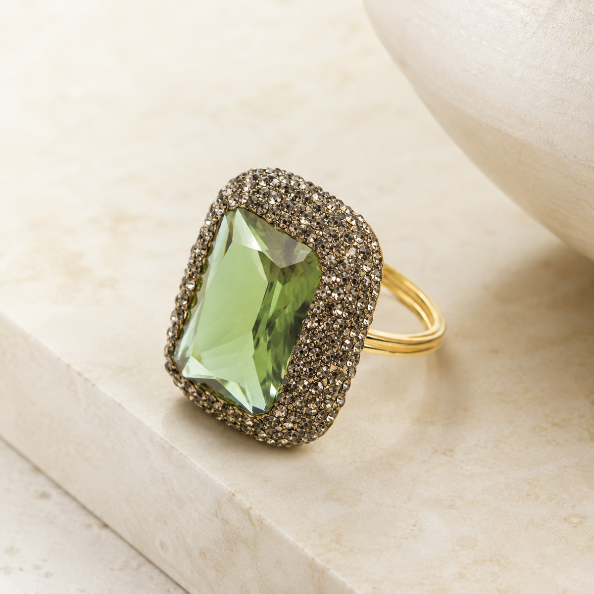 A statement ring with a faceted green stone and gold-tone details.