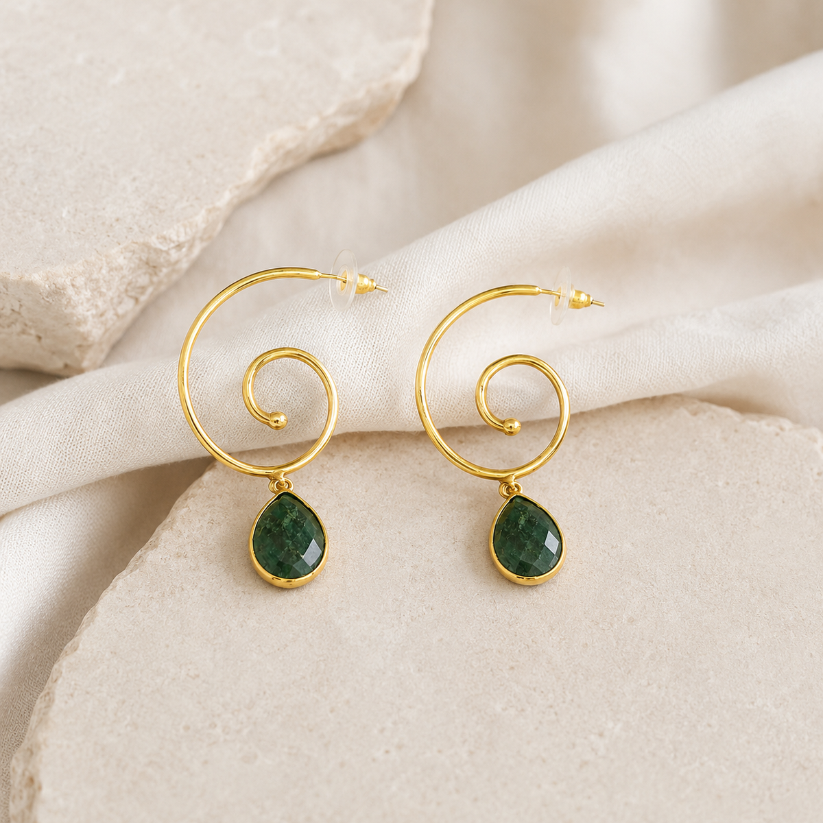 Pair of spiral drop earrings with green stones and a polished gold finish.