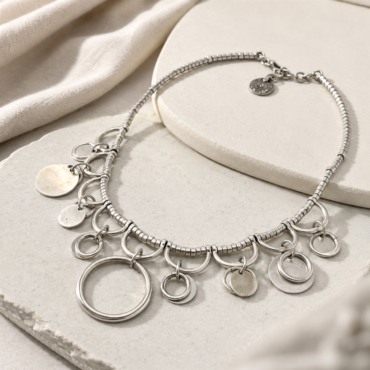 Angled view of the silver-tone necklace with dangling ring charms.