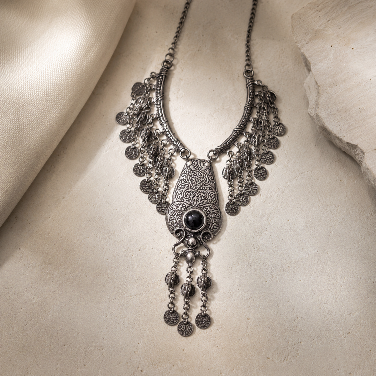 Detailed silver-tone necklace with a red stone center and layered fringe design.