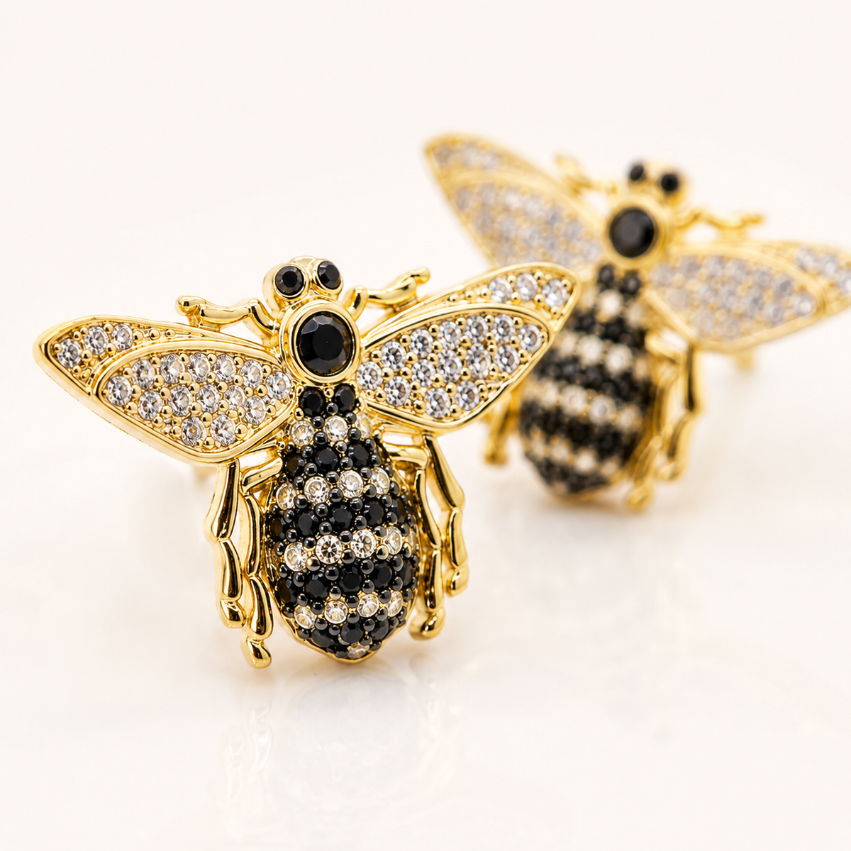 Close view of bee stud earrings with black CZ stones and gold plating.