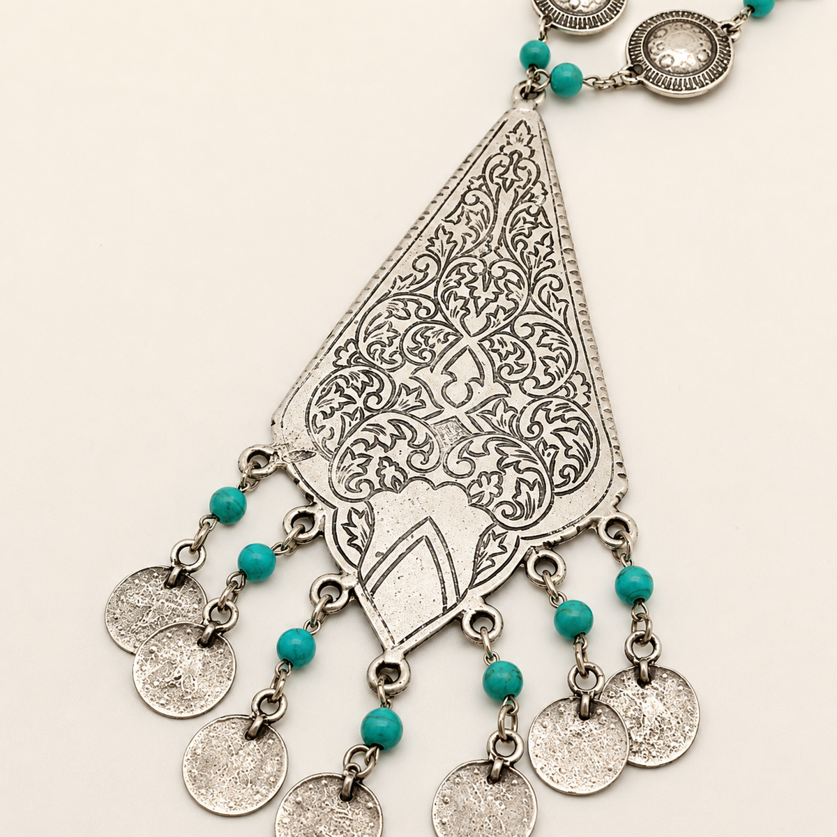 Close view of the turquoise beads and etched silver-tone pendant detail.
