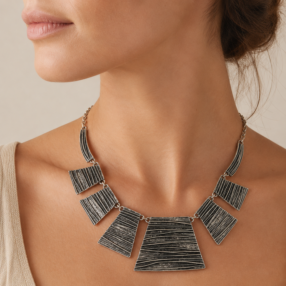 Silver-tone statement necklace with textured panel links on a white background.