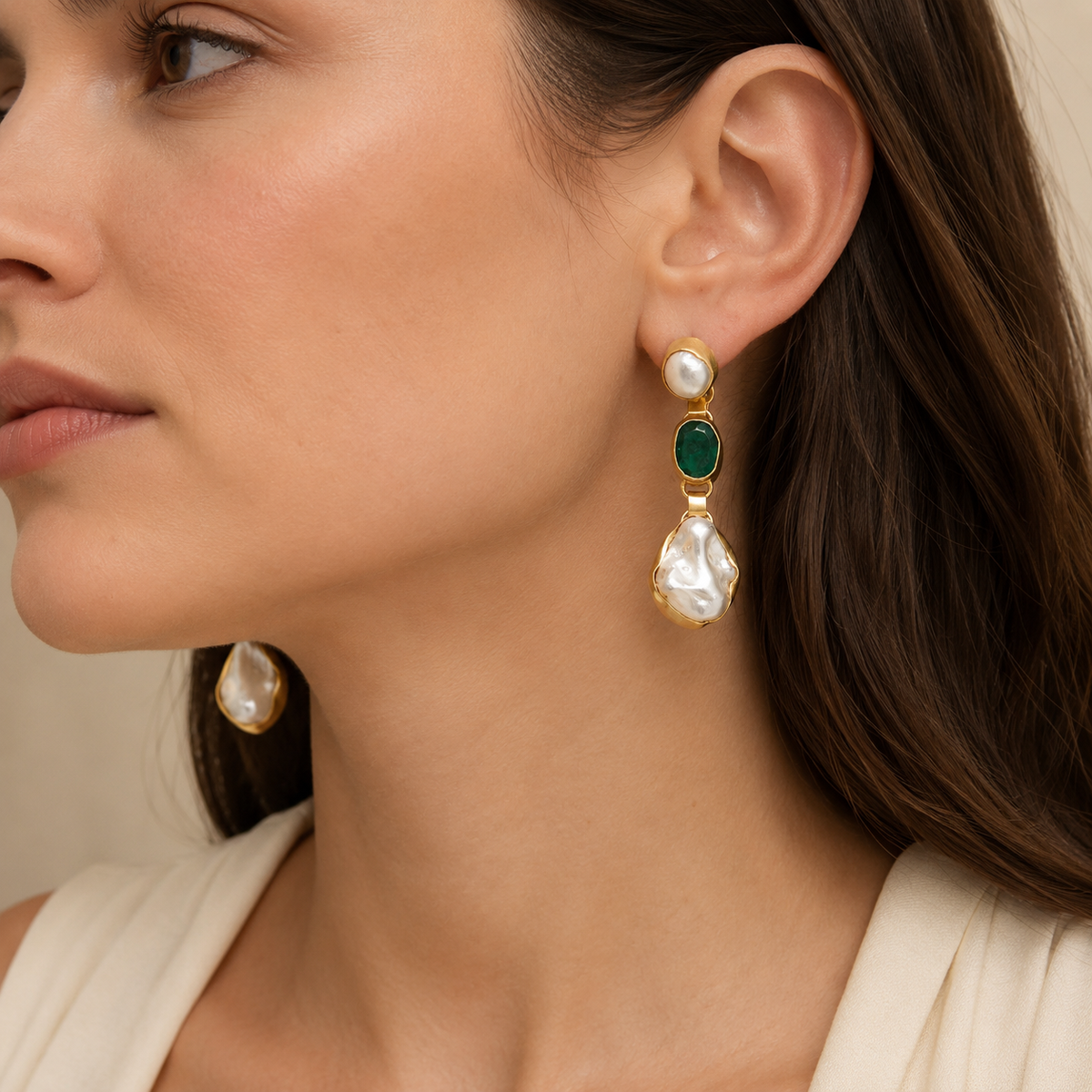 Pair of gold-plated drop earrings with emerald green stones and irregular pearl-like drops.