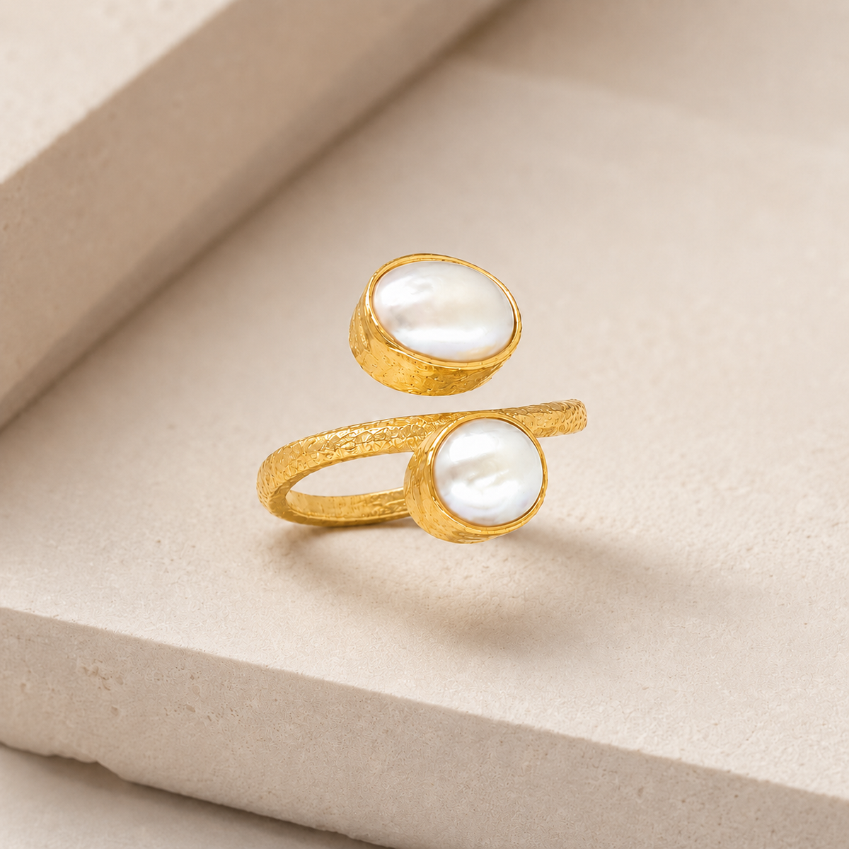 Two-stone gold-plated ring with pearl-like details.
