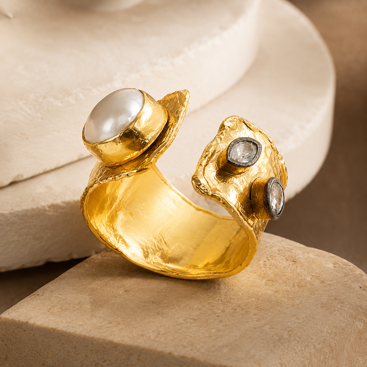 Angled view of a gold-plated open cuff ring with pearl-like and clear CZ details.