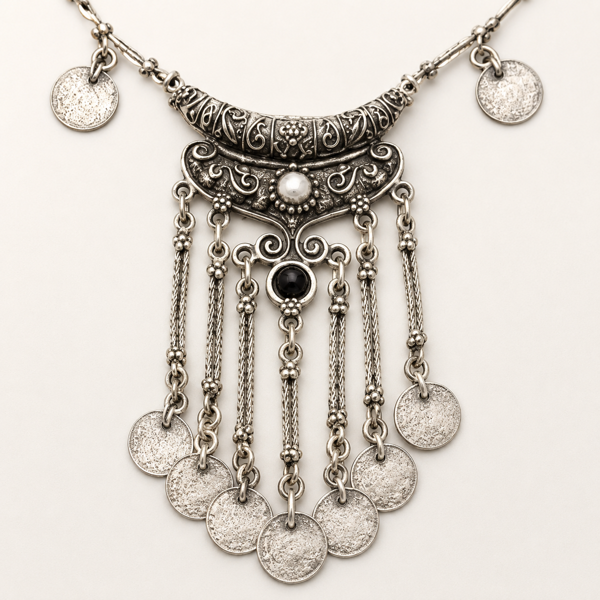 Close view of the ornate silver-tone pendant with a black stone center.
