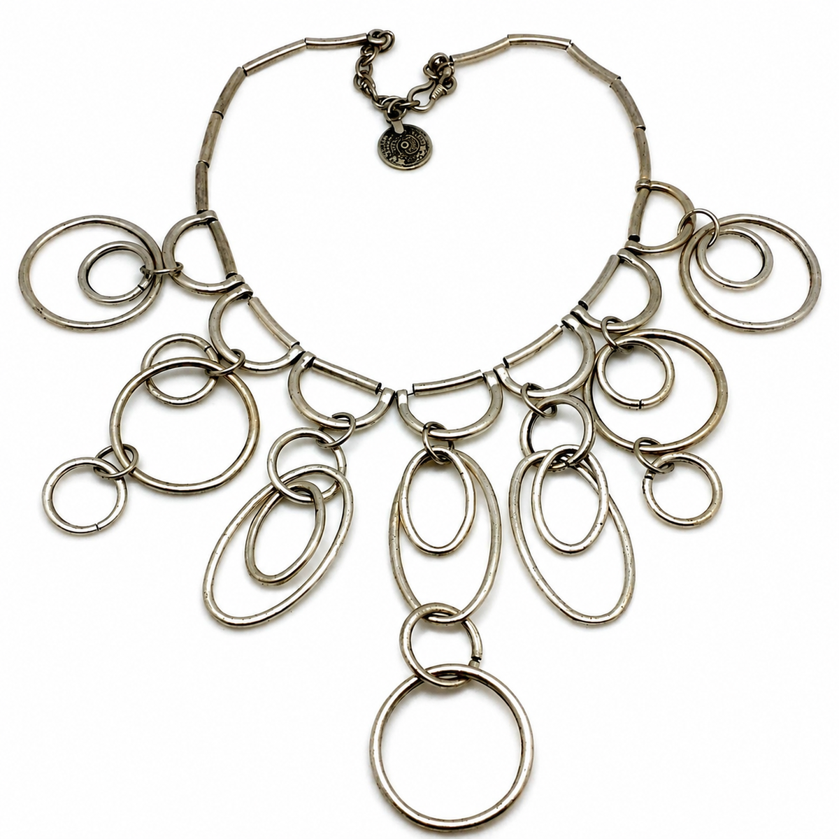 Silver-tone statement necklace with layered ring drops and a sculptural silhouette.