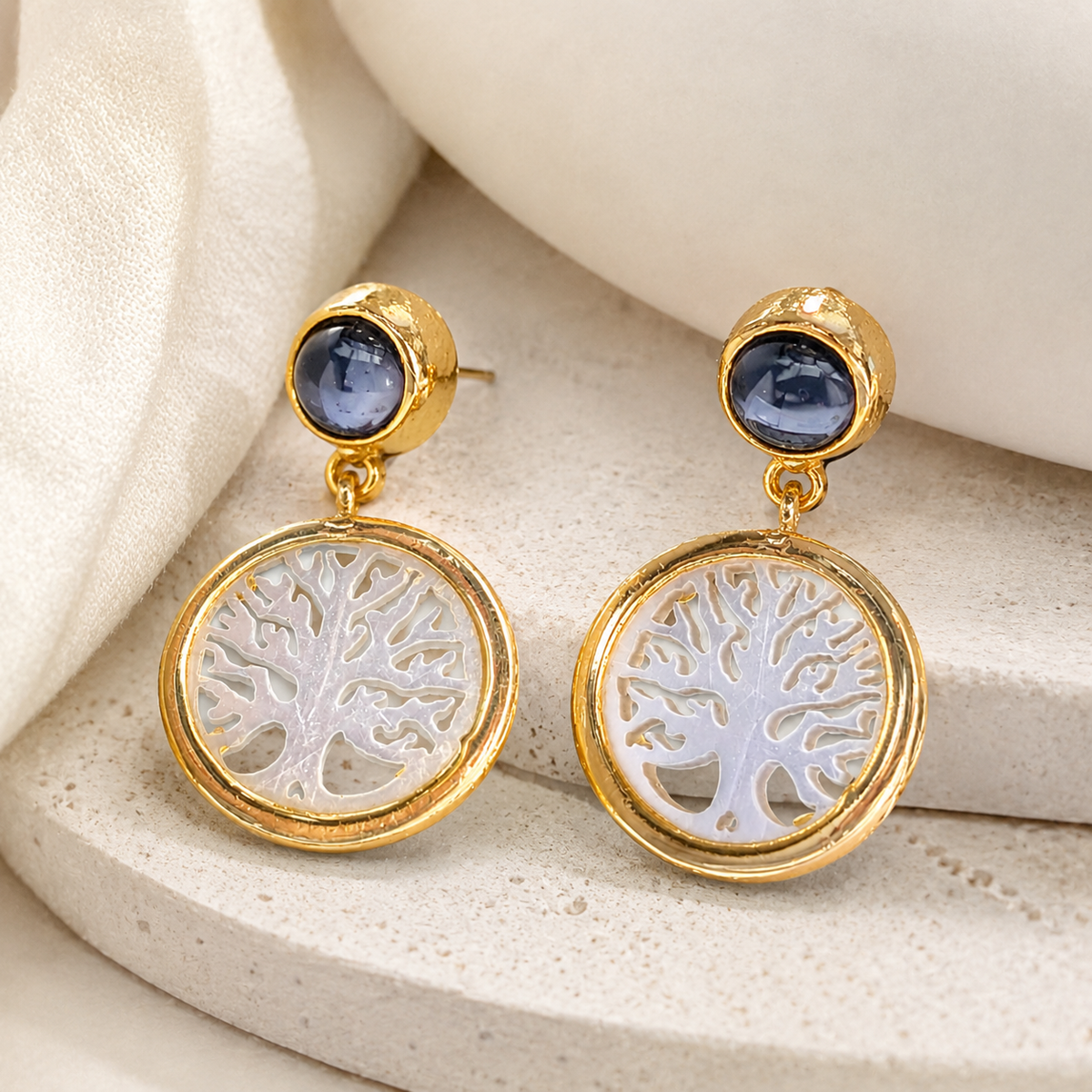 Angled view of gold-plated Tree of Life drop earrings with black onyx detail.