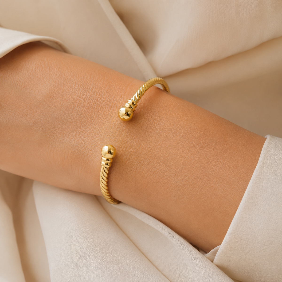 Gold-tone twisted open cuff bracelet shown from the front.